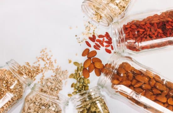 Clear glass jars filled with seeds and nuts, spilling out onto a white table
