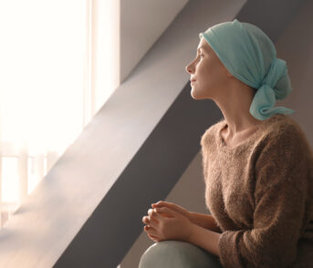 Young woman with cancer in headscarf indoors